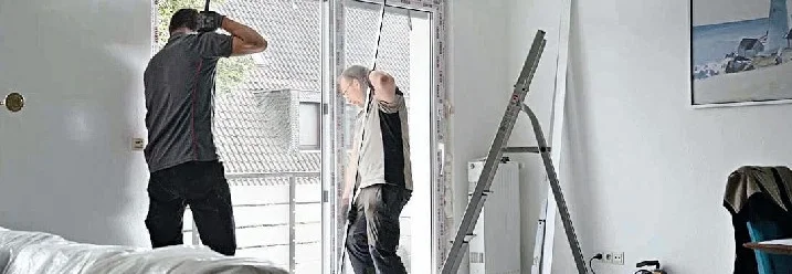 Zwei Personen montieren eine Terrassentür mit einer Wasserwaage.